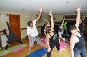 TPH residents and staff in side angle pose. Yoga's benefits for recovery include stress relief.