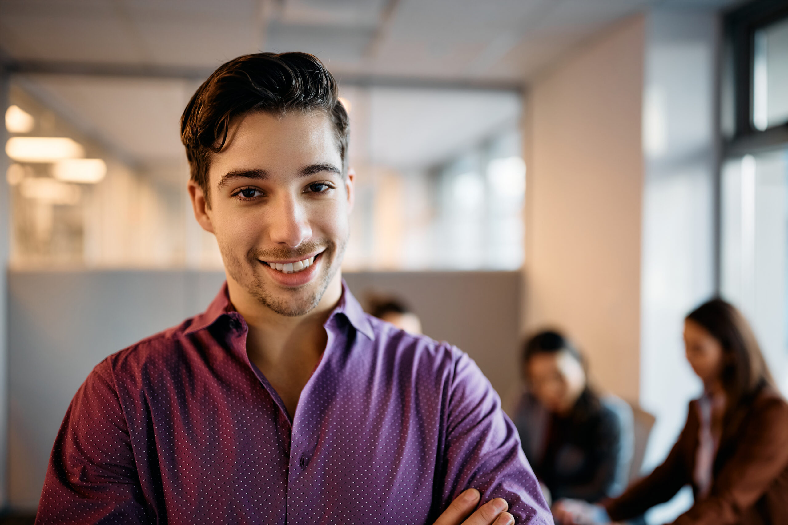 Young happy businessman in the office looking at camera.